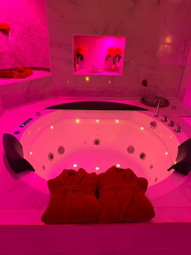 uma casa de banho rosa com uma banheira num quarto em Suite romantique avec jaccuzy à la gare de Montpellier em Montpellier