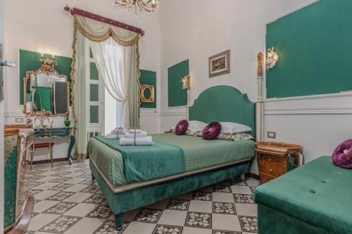 a bedroom with a green bed and a mirror at Palazzo Extravacanza in Polignano a Mare