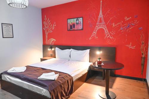 a bedroom with a bed and a red wall with the eiffel tower at Hotel Ida in Bansko