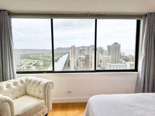 ein Schlafzimmer mit einem großen Fenster mit einem Sofa und einem Stuhl in der Unterkunft Waikiki Ocean View Penthouse 2/2 bdr/bath in Honolulu