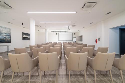a room with white chairs and a projection screen at Miramare Hotel in Zadar