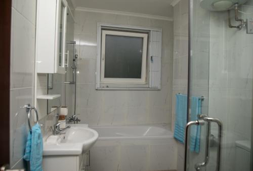 y baño con bañera, lavamanos y ducha. en Ridge Cozy Rooms en Accra