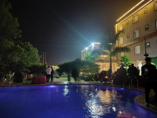 ein Schwimmbad in der Nacht mit Leuten um ihn herum in der Unterkunft Shivhari Hotel & Resort in Gwalior