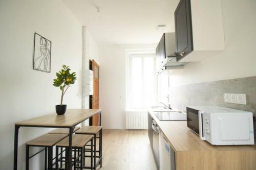 une cuisine avec un comptoir, une table et un four micro-ondes dans l'établissement Le Logis de la Gare - 4 min à pied de la gare, à Bourg-en-Bresse