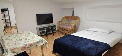 sypialnia z łóżkiem, krzesłem i telewizorem w obiekcie Atico CabezoDoce w mieście Calahorra