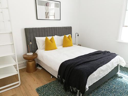 Un dormitorio con una cama grande con almohadas amarillas. en Beautiful Queen Room 1Min Walk to Station with 60Inch TV, en Sídney