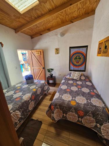 a bedroom with two beds in a room with a window at Hostal Likancabur in San Pedro de Atacama