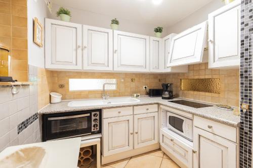 une cuisine avec des armoires blanches et un évier dans l'établissement maison climatisée dans jardin, à Torreilles