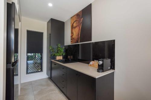 a kitchen with black cabinets and a counter with a microwave at Baligara Absolute Oceanfront Guest Suite in Bargara