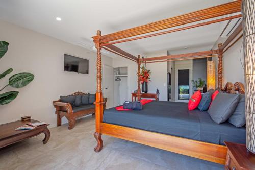 1 dormitorio con cama con dosel y sofá en Baligara Absolute Oceanfront Guest Suite en Bargara