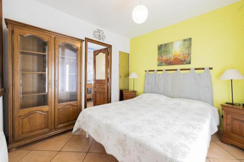 een slaapkamer met een wit bed en een houten kast bij maison dans jardin in Torreilles