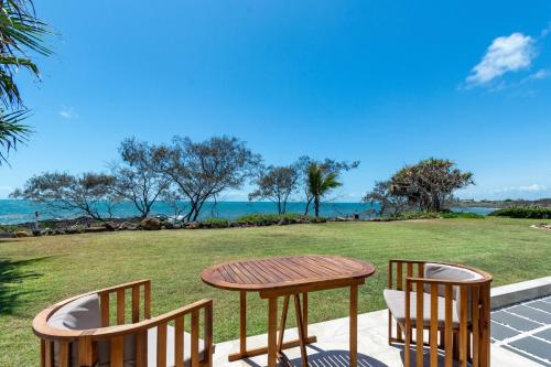 una mesa y 2 sillas en un patio con vistas al océano en Baligara Absolute Oceanfront Guest Suite en Bargara