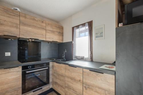 - une cuisine avec des appareils noirs et des armoires en bois dans l'établissement Les Chardons - Apt duplex vue montagne, à Saint-Léger-les-Mélèzes