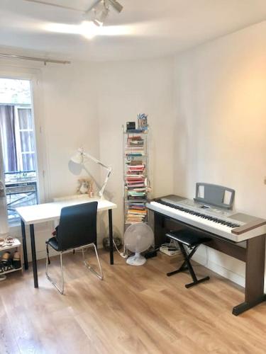 Cette chambre dispose d'un piano et d'un bureau avec un ordinateur portable. dans l'établissement Enchanting Retreat in the Heart of the Latin Quarter - Entire Studio for yourself, à Paris