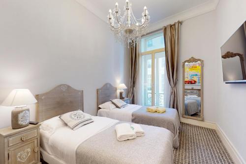 Habitación con 2 camas, espejo y lámpara de araña. en Silver Suite Five Stars Holiday House, en Niza