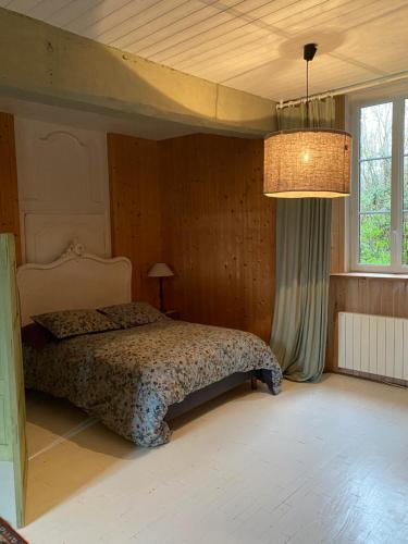 - une chambre avec un lit et un lustre dans l'établissement Le 44, à Baguer-Pican