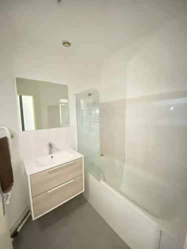 La salle de bains blanche est pourvue d'un lavabo et d'une douche. dans l'établissement T2 en RDC calme et central 5min à pieds de la gare, à Roanne