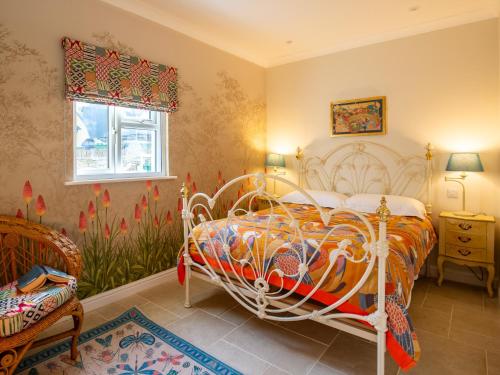 a bedroom with a bed and a chair and a window at Sundown Lodge in Chipping Campden