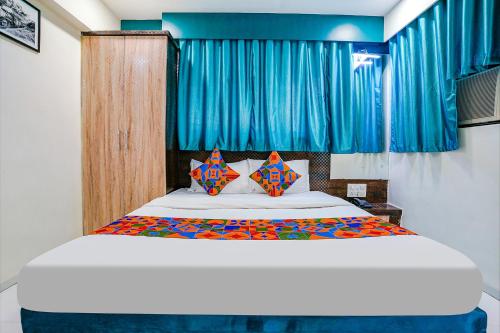 a bedroom with a large bed with blue curtains at FabExpress Bindra Elite in Mumbai