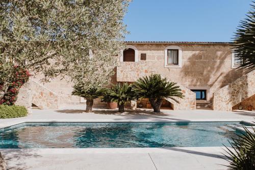 une piscine en face d'un bâtiment avec des arbres dans l'établissement Sa Talaia Blanca, à Muro