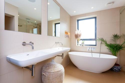 a bathroom with a large white sink and a tub at Veeve - Exalted Living in London