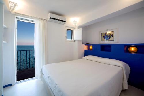 a bedroom with a white bed and a large window at Hotel Saraceno in Giglio Porto