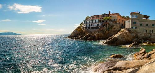 a building on a cliff next to the water at Hotel Saraceno in Giglio Porto