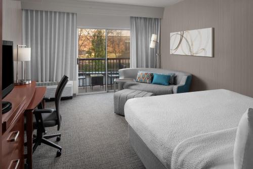a hotel room with a bedroom with a bed and a desk at Courtyard by Marriott Raleigh North/Triangle Town Center in Raleigh