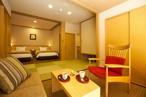 um quarto de hotel com um sofá e um quarto com duas camas em 奥日光森のホテル em Yumoto