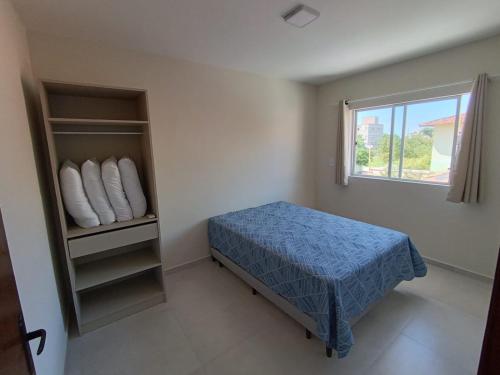 a small bedroom with a bed and a window at Residencial Brisa do Mar 2 in Bombinhas