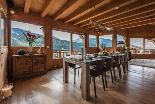 a dining room with a table and chairs and mountains at Chalet Omaroo Morzine - by EMERALD STAY in Morzine