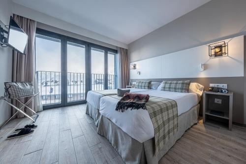 um quarto de hotel com uma cama e uma grande janela em Apartamentos Caribou em Pas de la Casa