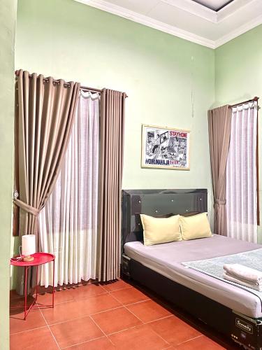 a bedroom with a bed with curtains and a table at Telu.Telu Solo in Solo
