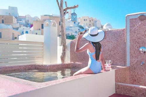 a woman in a blue dress and hat sitting on a ledge at Luxury Villas Hariton in Emporio
