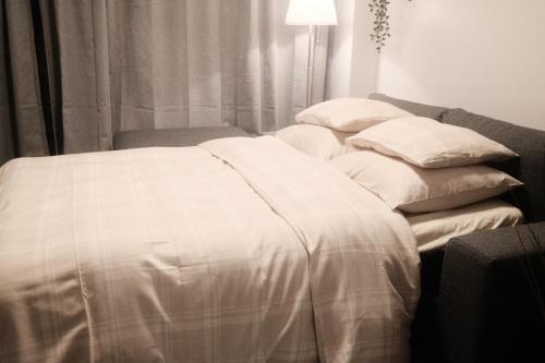 een bed met witte lakens en kussens in een kamer bij Tiny House : Felix the Cat in La-Roche-en-Ardenne