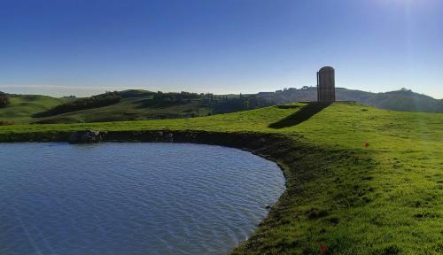 a clock tower on a hill next to a body of water at Tenuta d'Arbia, Siena in Monteroni dʼArbia
