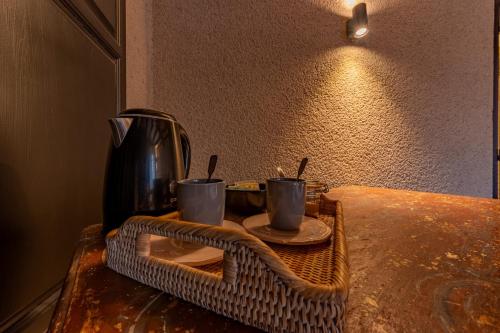 uma mesa com duas chávenas de café e uma cafeteira em Les chambres du Presbytère em Montagudet