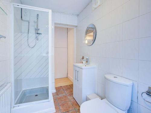 uma casa de banho branca com um chuveiro e um WC. em Pass the Keys Charming 2 Bedroom House Good Transport and Parking em Londres