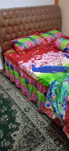 un letto con coperta colorata e cuscini sopra di KHAIRI HOMESTAY a Bukittinggi