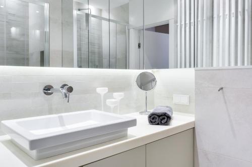 Baño blanco con lavabo y espejo en Elite Apartments Rezydencja Marina, en Gdansk