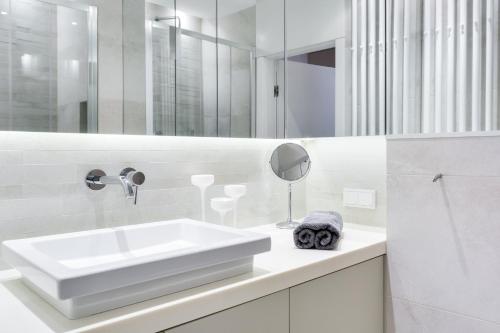 biała łazienka z umywalką i lustrem w obiekcie Elite Apartments Rezydencja Marina w Gdańsku