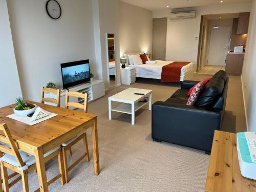 a living room with a couch and a table and a bed at Tasha's Apartments on Morphett in Adelaide