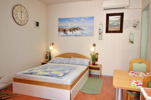 a bedroom with a bed and a table and a clock at Apartment Renata in Šilo