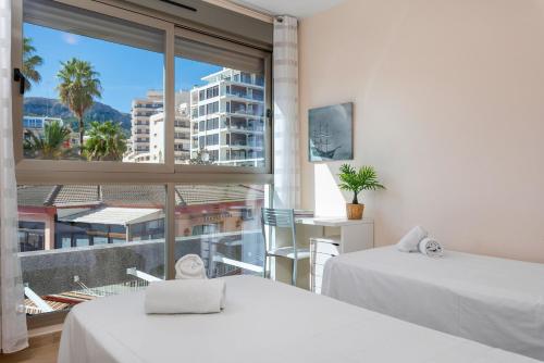 a bedroom with two beds and a large window at Apartamento Melior 2C - PlusHolidays in Calpe