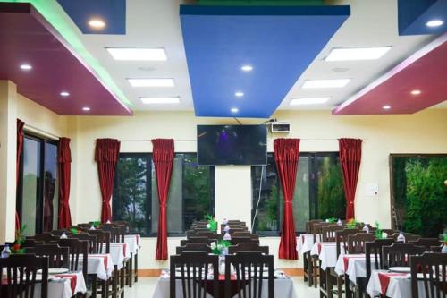 a banquet hall with tables and chairs and a tv at Doleshwor Village Resort and Farm House Pvt Ltd in Bhaktapur