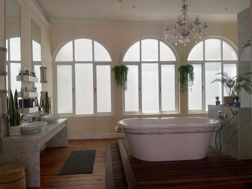 a bathroom with a large tub and three windows at Cosy city stay in Cape Town