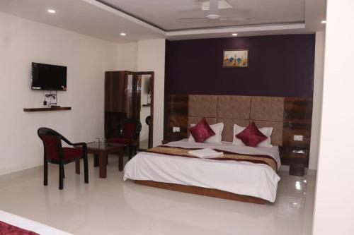 a bedroom with a bed and a table with a chair at Hotel Grand Exotica in Haridwār