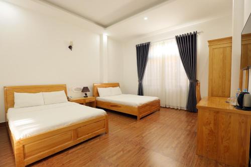 a bedroom with two beds and a window at Maxim Hotel in Da Lat