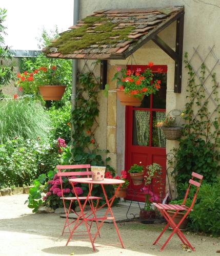 une table et des chaises devant une maison avec une porte rouge dans l'établissement La Grange du Bourg, à Deneuille-les-Mines