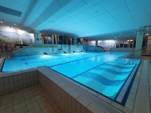 una gran piscina con iluminación azul en un edificio en Ferienwohnung Winklworld 2 mit Hallenbad und Sauna inklusive aktivCARD, en Sankt Englmar